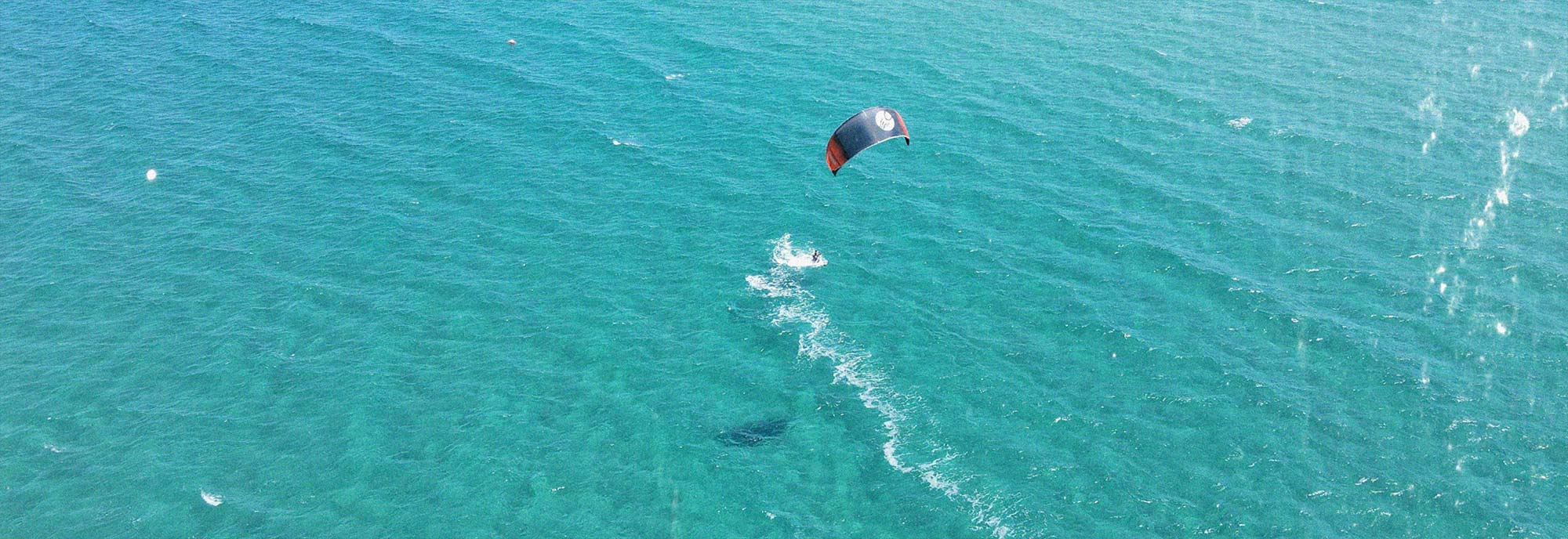Kite-Surfer auf türkisblauem Wasser am Nido Beach in Posada, Sardinien